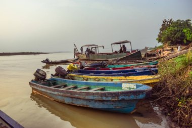 Delta State, Nijerya - 9 Aralık 2021 Nijer nehrinin kıyısında güzel bir Sunrise 'ı dengeleyen yerel kanolar yapıldı. Nehir kıyısında balıkçı tekneleri. Bir su yüzeyinde yansıma.