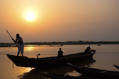 Delta State, Nijerya - 9 Aralık 2021 Nijer nehrinin kıyısında güzel bir Sunrise 'ı dengeleyen yerel kanolar yapıldı. Nehir kıyısında balıkçı tekneleri. Bir su yüzeyinde yansıma.