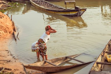 Delta State, Nijerya - 9 Aralık 2021 Nijer nehrinin kıyısında güzel bir Sunrise 'ı dengeleyen yerel kanolar yapıldı. Nehir kıyısında balıkçı tekneleri. Bir su yüzeyinde yansıma.