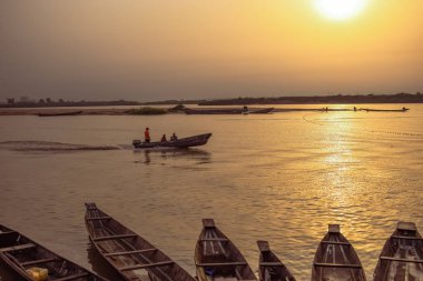 Delta State, Nijerya - 9 Aralık 2021 Nijer nehrinin kıyısında güzel bir Sunrise 'ı dengeleyen yerel kanolar yapıldı. Nehir kıyısında balıkçı tekneleri. Bir su yüzeyinde yansıma.