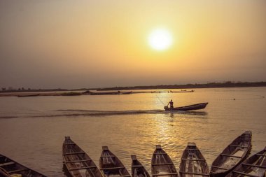 Delta State, Nijerya - 9 Aralık 2021 Nijer nehrinin kıyısında güzel bir Sunrise 'ı dengeleyen yerel kanolar yapıldı. Nehir kıyısında balıkçı tekneleri. Bir su yüzeyinde yansıma.