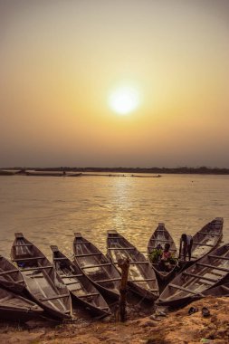 Delta State, Nijerya - 9 Aralık 2021 Nijer nehrinin kıyısında güzel bir Sunrise 'ı dengeleyen yerel kanolar yapıldı. Nehir kıyısında balıkçı tekneleri. Bir su yüzeyinde yansıma.