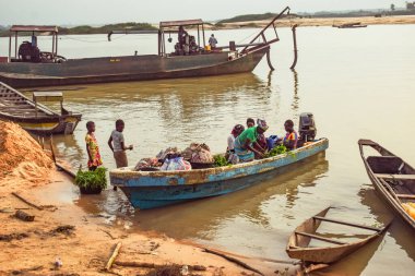 Delta State, Nijerya - 9 Aralık 2021: Nijer Nehri kıyısında yerel olarak yapılmış kanolar. Nehir kıyısında balıkçı tekneleri. Bir su yüzeyinde yansıma.