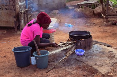 Opialu, Benue State - 6 Mart 2021: Odun odunuyla dışarıda yemek pişiren Afrikalı Kadın