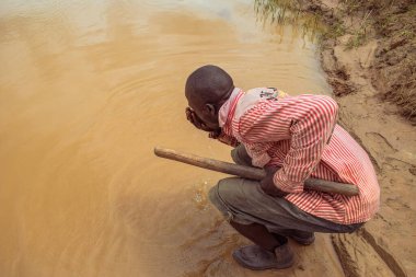 Delta State, Nijerya - 9 Aralık 2021: Nehirden su içen Afrikalı adam, Nijerya