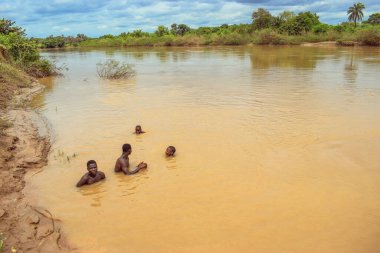 Delta State, Nijerya - 9 Aralık 2021: Nehirde kirli suyla yüzen Afrikalı erkekler, Nijerya