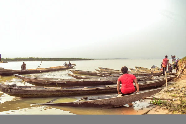 stock image Delta State, Nigeria - December 9, 2021: Locally made Canoes by a Riverside on River Niger. Fishing Boats by a River Bank. Reflection on a Water Surface.