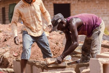 Abaji, FCT Abuja - 20 Ocak 2023: Kırsal kesimde 3 odalı bir apartman dairesi inşaatı. İnşaat alanında çalışan tamirciler..