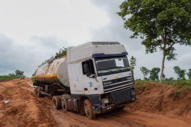 Loko, Nasarawa, Nijerya - 06 Ağustos 2021: Yağmur mevsiminde çamurlu yol. Araçlar kötü yola saplandı ve kazaya neden oldu..