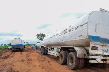 Loko, Nasarawa, Nijerya - 06 Ağustos 2021: Yağmur mevsiminde çamurlu yol. Araçlar kötü yola saplandı ve kazaya neden oldu..