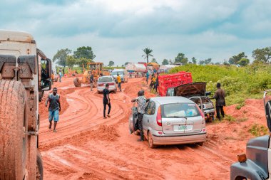 Loko, Nasarawa, Nijerya - 06 Ağustos 2021: Yağmur mevsiminde çamurlu yol. Araçlar kötü yola saplandı ve kazaya neden oldu..