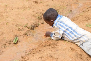 Abuja Nijerya - 02 Ağustos 2021: Güneşli bir günde Afrikalı Çocuk Kum ile Oynuyor. Üçüncü Dünya Çocuklarıyla Eğlence Zamanı