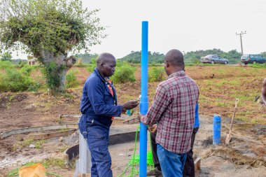 Jos East, Plateau State, Nijerya - 12 Mayıs 2021: Kırsal kesimlerde elle su kuyusu kurulumu. Nijerya Afrika 'daki SDG Hedefleri. Bir grup Afrikalı elle su pompalamaya çalışıyor..