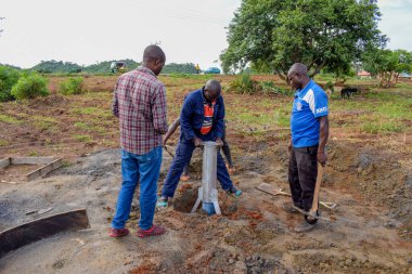 Jos East, Plateau State, Nijerya - 12 Mayıs 2021: Kırsal kesimlerde elle su kuyusu kurulumu. Nijerya Afrika 'daki SDG Hedefleri. Bir grup Afrikalı elle su pompalamaya çalışıyor..