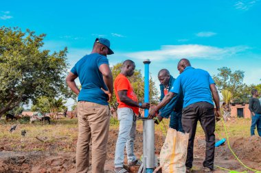 Jos East, Plateau State, Nijerya - 12 Mayıs 2021: Kırsal kesimlerde elle su kuyusu kurulumu. Nijerya Afrika 'daki SDG Hedefleri. Bir grup Afrikalı elle su pompalamaya çalışıyor..