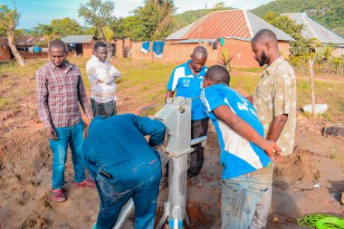Jos East, Plateau State, Nijerya - 12 Mayıs 2021: Kırsal kesimlerde elle su kuyusu kurulumu. Nijerya Afrika 'daki SDG Hedefleri. Bir grup Afrikalı elle su pompalamaya çalışıyor..
