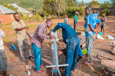 Jos East, Plateau State, Nijerya - 12 Mayıs 2021: Kırsal kesimlerde elle su kuyusu kurulumu. Nijerya Afrika 'daki SDG Hedefleri. Bir grup Afrikalı elle su pompalamaya çalışıyor..