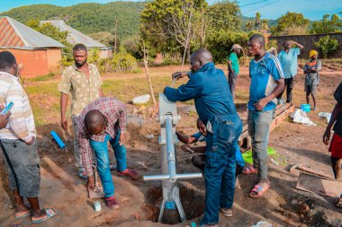 Jos East, Plateau State, Nijerya - 12 Mayıs 2021: Kırsal kesimlerde elle su kuyusu kurulumu. Nijerya Afrika 'daki SDG Hedefleri. Bir grup Afrikalı elle su pompalamaya çalışıyor..