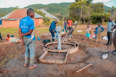 Jos East, Plateau State, Nijerya - 12 Mayıs 2021: Kırsal kesimlerde elle su kuyusu kurulumu. Nijerya Afrika 'daki SDG Hedefleri. Bir grup Afrikalı elle su pompalamaya çalışıyor..