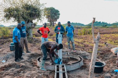 Jos East, Plateau State, Nijerya - 12 Mayıs 2021: Kırsal kesimlerde elle su kuyusu kurulumu. Nijerya Afrika 'daki SDG Hedefleri. Bir grup Afrikalı elle su pompalamaya çalışıyor..