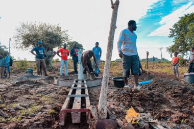 Jos East, Plateau State, Nijerya - 12 Mayıs 2021: Kırsal kesimlerde elle su kuyusu kurulumu. Nijerya Afrika 'daki SDG Hedefleri. Bir grup Afrikalı elle su pompalamaya çalışıyor..