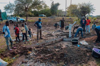 Jos East, Plateau State, Nijerya - 12 Mayıs 2021: Kırsal kesimlerde elle su kuyusu kurulumu. Nijerya Afrika 'daki SDG Hedefleri. Bir grup Afrikalı elle su pompalamaya çalışıyor..