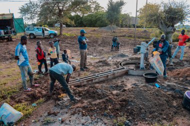 Jos East, Plateau State, Nijerya - 12 Mayıs 2021: Kırsal kesimlerde elle su kuyusu kurulumu. Nijerya Afrika 'daki SDG Hedefleri. Bir grup Afrikalı elle su pompalamaya çalışıyor..