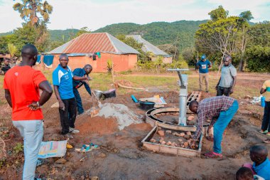 Jos East, Plateau State, Nijerya - 12 Mayıs 2021: Kırsal kesimlerde elle su kuyusu kurulumu. Nijerya Afrika 'daki SDG Hedefleri. Bir grup Afrikalı elle su pompalamaya çalışıyor..