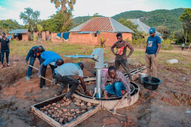 Jos East, Plateau State, Nijerya - 12 Mayıs 2021: Kırsal kesimlerde elle su kuyusu kurulumu. Nijerya Afrika 'daki SDG Hedefleri. Bir grup Afrikalı elle su pompalamaya çalışıyor..