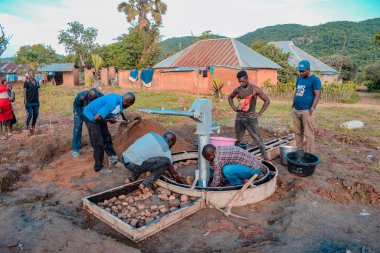 Jos East, Plateau State, Nijerya - 12 Mayıs 2021: Kırsal kesimlerde elle su kuyusu kurulumu. Nijerya Afrika 'daki SDG Hedefleri. Bir grup Afrikalı elle su pompalamaya çalışıyor..
