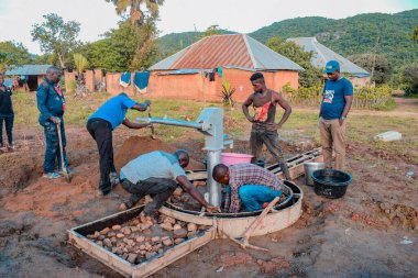 Jos East, Plateau State, Nijerya - 12 Mayıs 2021: Kırsal kesimlerde elle su kuyusu kurulumu. Nijerya Afrika 'daki SDG Hedefleri. Bir grup Afrikalı elle su pompalamaya çalışıyor..