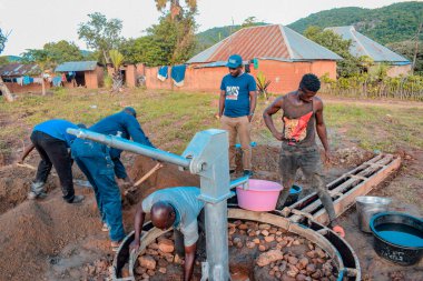 Jos East, Plateau State, Nijerya - 12 Mayıs 2021: Kırsal kesimlerde elle su kuyusu kurulumu. Nijerya Afrika 'daki SDG Hedefleri. Bir grup Afrikalı elle su pompalamaya çalışıyor..