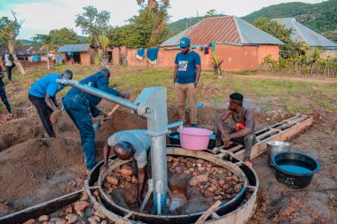 Jos East, Plateau State, Nijerya - 12 Mayıs 2021: Kırsal kesimlerde elle su kuyusu kurulumu. Nijerya Afrika 'daki SDG Hedefleri. Bir grup Afrikalı elle su pompalamaya çalışıyor..