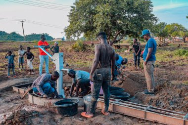 Jos East, Plateau State, Nijerya - 12 Mayıs 2021: Kırsal kesimlerde elle su kuyusu kurulumu. Nijerya Afrika 'daki SDG Hedefleri. Bir grup Afrikalı elle su pompalamaya çalışıyor..