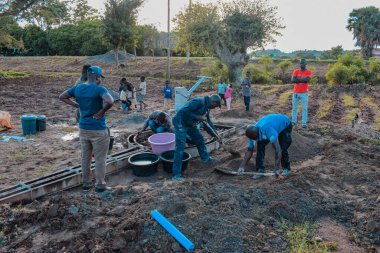 Jos East, Plateau State, Nijerya - 12 Mayıs 2021: Kırsal kesimlerde elle su kuyusu kurulumu. Nijerya Afrika 'daki SDG Hedefleri. Bir grup Afrikalı elle su pompalamaya çalışıyor..