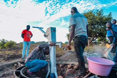 Jos East, Plateau State, Nijerya - 12 Mayıs 2021: Kırsal kesimlerde elle su kuyusu kurulumu. Nijerya Afrika 'daki SDG Hedefleri. Bir grup Afrikalı elle su pompalamaya çalışıyor..