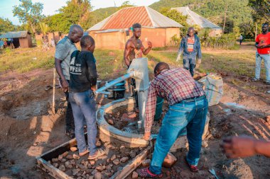 Jos East, Plateau State, Nijerya - 12 Mayıs 2021: Kırsal kesimlerde elle su kuyusu kurulumu. Nijerya Afrika 'daki SDG Hedefleri. Bir grup Afrikalı elle su pompalamaya çalışıyor..