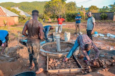 Jos East, Plateau State, Nijerya - 12 Mayıs 2021: Kırsal kesimlerde elle su kuyusu kurulumu. Nijerya Afrika 'daki SDG Hedefleri. Bir grup Afrikalı elle su pompalamaya çalışıyor..