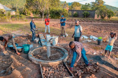 Jos East, Plateau State, Nijerya - 12 Mayıs 2021: Kırsal kesimlerde elle su kuyusu kurulumu. Nijerya Afrika 'daki SDG Hedefleri. Bir grup Afrikalı elle su pompalamaya çalışıyor..