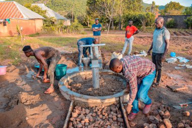 Jos East, Plateau State, Nijerya - 12 Mayıs 2021: Kırsal kesimlerde elle su kuyusu kurulumu. Nijerya Afrika 'daki SDG Hedefleri. Bir grup Afrikalı elle su pompalamaya çalışıyor..