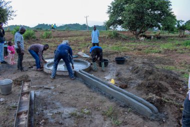 Jos East, Plateau State, Nijerya - 12 Mayıs 2021: Elle su pompalamak için çalışan bir grup Afrikalı.