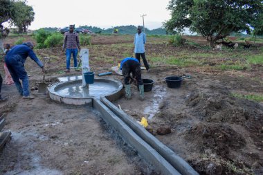 Jos East, Plateau State, Nijerya - 12 Mayıs 2021: Elle su pompalamak için çalışan bir grup Afrikalı.