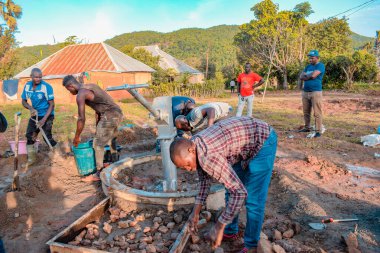 Jos East, Plateau State, Nijerya - 12 Mayıs 2021: Elle su pompalamak için çalışan bir grup Afrikalı.