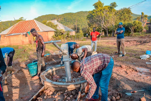 Jos East, Plateau State, Nijerya - 12 Mayıs 2021: Kırsal kesimlerde elle su kuyusu kurulumu. Nijerya Afrika 'daki SDG Hedefleri. Bir grup Afrikalı elle su pompalamaya çalışıyor..