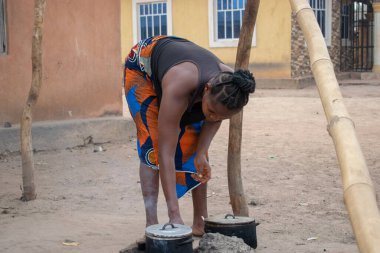 Opialu, Benue State - 6 Mart 2021: Yakacak odunuyla dışarıda pişen olgun Afrikalı Kadın