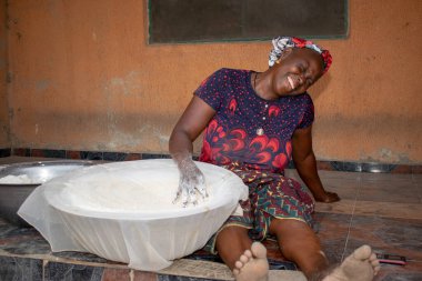 Opialu, Benue State, Nijerya - 6 Mart 2021: Gülümseyen Orta Çağ Afrikalı Kadın Cassava unu Süreci sırasında Yerde Çalışıyor ve Oturuyor (Garri)