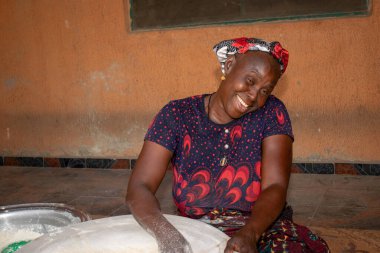 Opialu, Benue State, Nijerya - 6 Mart 2021: Gülümseyen Orta Çağ Afrikalı Kadın Cassava unu Süreci sırasında Yerde Çalışıyor ve Oturuyor (Garri)