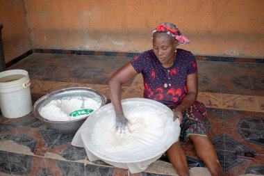 Opialu, Benue State, Nijerya - 6 Mart 2021: Gülümseyen Orta Çağ Afrikalı Kadın Cassava unu Süreci sırasında Yerde Çalışıyor ve Oturuyor (Garri)