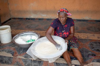 Opialu, Benue State, Nijerya - 6 Mart 2021: Gülümseyen Orta Çağ Afrikalı Kadın Cassava unu Süreci sırasında Yerde Çalışıyor ve Oturuyor (Garri)