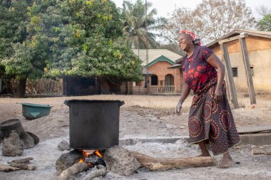 Opialu, Benue State - 6 Mart 2021: Kırsal bir ortamda odun kullanan Gülümseyen Orta Çağ Afrikalı Kadın